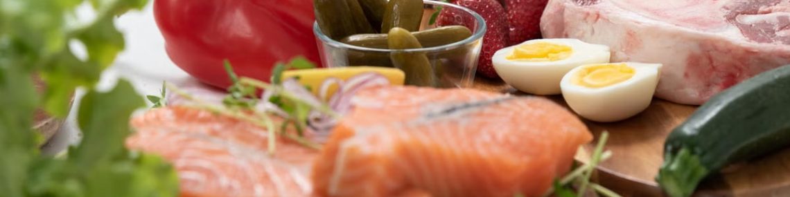 A vibrant assortment of fresh salmon, eggs, vegetables, and fruits arranged on a wooden platter.